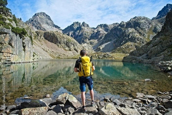 Fototapeta Man facing away contemplates the Ibones de Arriel and surrounding peaks in the Spanish Pyrenees,