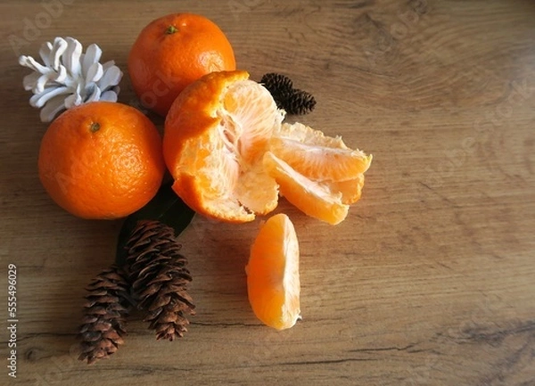 Fototapeta Mandarin slices on a wooden table with Christmas cones
