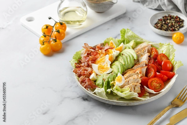 Fototapeta Cobb salad with bacon, avocado, tomato, grilled chicken, eggs isolated on  white background. American salad. Healthy food.