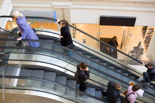 Fototapeta Peoples on escalators in a mall. Motion blur