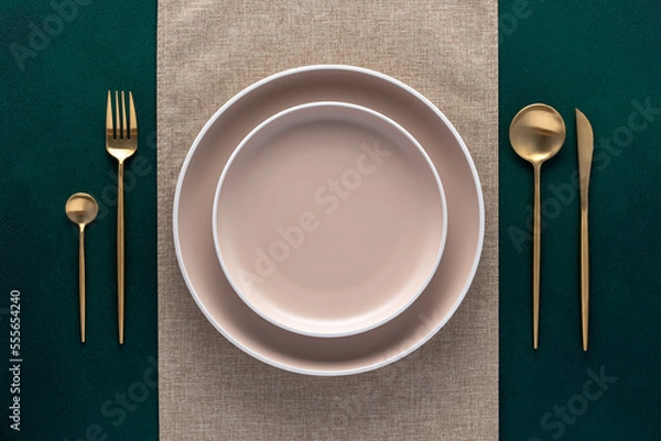 Obraz Festive place setting with beige napkin. Empty plates and gold cutlery on dark green background. Top view. Dining table in luxury restaurant. Card or menu template, flat design. Tableware, crockery.