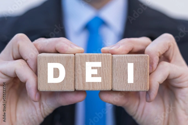 Fototapeta Man holding wooden cubes with abbreviation: DEI. Concept of DEI Diversity Equality Inclusion. Multiracial Multicultural Community Belonging Human Rights.