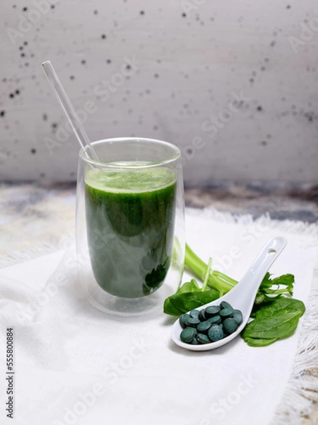 Fototapeta spirulina smoothie with a few leafs on a white background