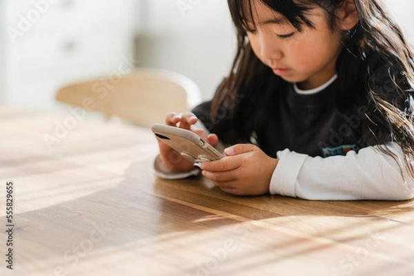 Obraz スマートフォンを見る幼い日本人の女の子