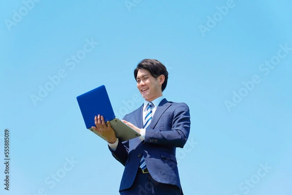 Fototapeta 屋外でパソコンを使うビジネスマン