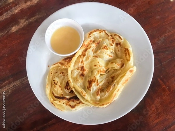 Fototapeta Abstract process photo of Roti canai with a cup of condensed milk as a sweet recipe in Thailand. That also calls roti prata which is an Indian flatbread dish can be cooked sweet or savoury variations