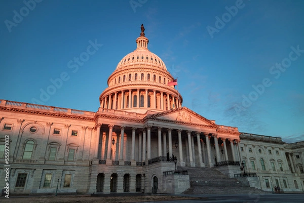 Fototapeta The beautiful sight of the US Capitol building bathed in morning sunlight. The east side of the iconic structure is illuminated by the rising sun, creating a stunning scene in Washington, DC.