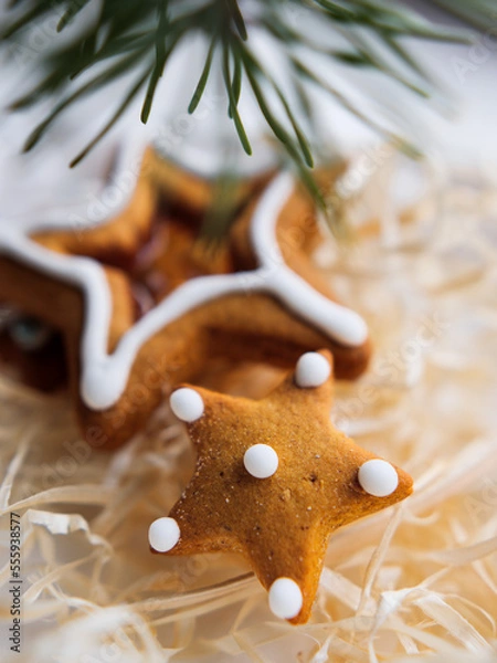 Obraz Christmas gingerbread cookies in the shape of a star lie in a white box next to a pine branch. Christmas cookies with frosting. gingerbread lies on a white table.