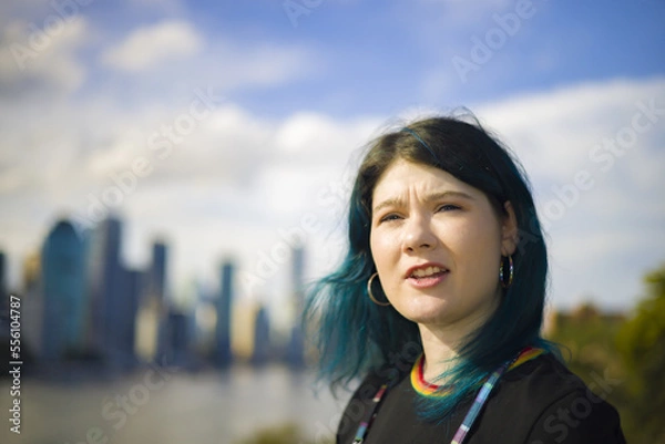 Fototapeta A beautiful alternative young woman smiling and happy with Brisbane's CBD and river in the background, kangaroo point cliffs, Queensland Australia
