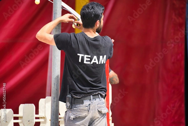 Fototapeta man work on the tent organizing, assistant, activity, voluntary, music festival, organiser, job, camp, live, open air, party, club, perform, lamp, theater, arena, lighting, profession, supervise,