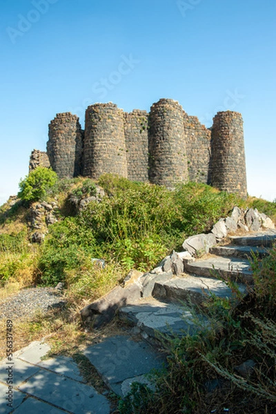 Obraz the ancient walls of the stone castle of the fortress with round brick towers are partially destroyed. Amberd ancient fortress in Armenia against the blue sky. Historical and cultural value