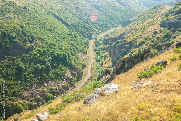 Fototapeta Automobile road running between high mountains in summer. top view of the road medu high mountains from both sides