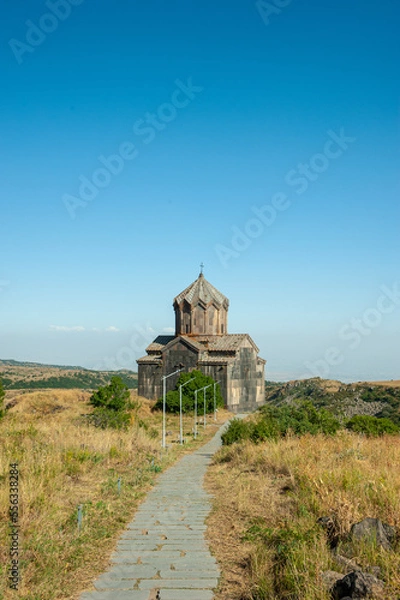 Obraz Christian church made of stone tuff in armenia of an ancient building in the mountains against the backdrop of beautiful nature and blue sky. Faith in God and Religion, Tourism and Cultural Heritage