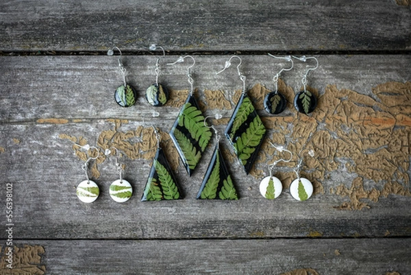 Obraz Close up earrings with fern leaves set concept photo. Handmade jewelry. Top view photography with wooden display on background. High quality picture for wallpaper, travel blog, magazine, article
