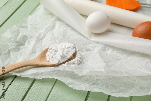 Fototapeta Baking paper with spoon of flour and eggs on green wooden background