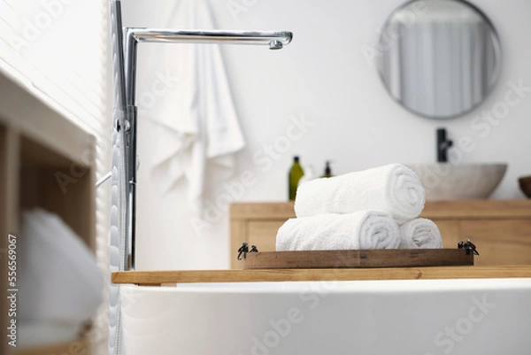 Fototapeta Rolled bath towels on tub tray in bathroom