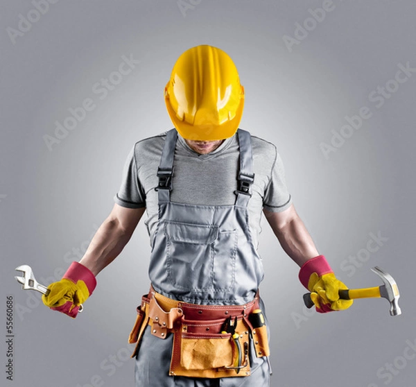 Obraz builder in a helmet with a hammer and a wrench