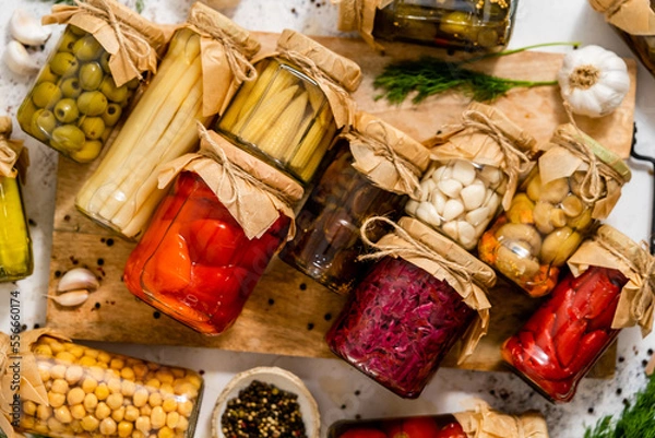Fototapeta Jars with pickles on cutting board