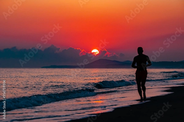 Obraz person walking on the beach at sunset