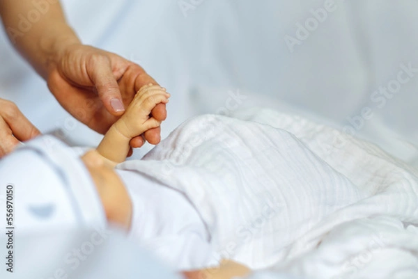 Fototapeta Close-up little hand of child and adult hands. The newborn baby sleeping after birth.