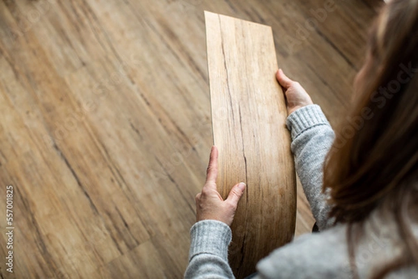 Fototapeta Woman choosing laminate floor design from samples in flooring store