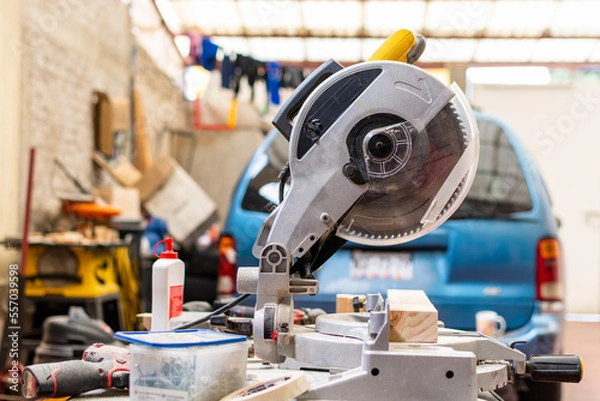 Fototapeta yellow miter saw on workbench next to more woodworking tool
