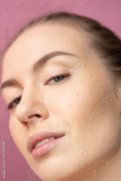 Fototapeta Girl's face with water drops on her face Looks at the camera Blue eyes Close up Horizontal frame Purple background Beauty ,Cosmeics,Fashion Open mouth