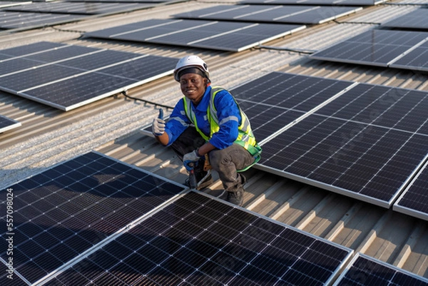Obraz Engineer on rooftop sitting next to solar panels photo voltaic smiling portrait