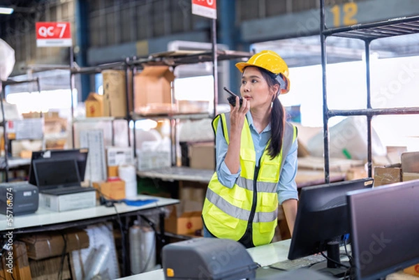 Fototapeta Worker working in large depot storage warehouse hold radio walkie talkie to team at cashier counter