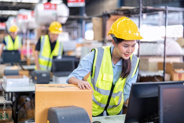 Fototapeta Worker working in the large depot storage warehouse happy smiling packing box at cashier counter
