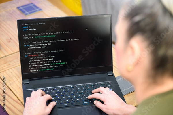 Fototapeta Coding in the house, a woman writing code on a laptop for an app or website while working from home