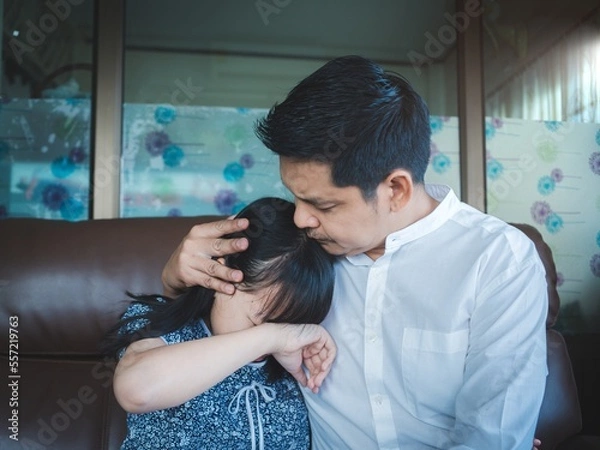 Fototapeta Loving daddy embracing small girl at home,Caring worry asian man hugging little daughter, Comforting his upset child,Father soothing crying depressed kid