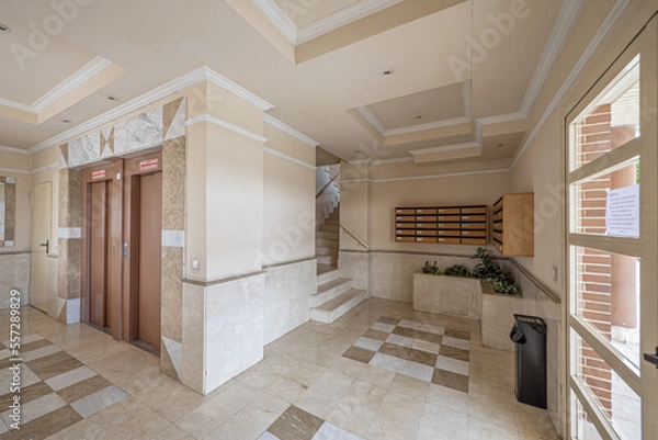 Fototapeta Portal of a building with light colored marble tiles and twin elevators