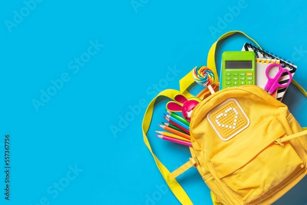 Fototapeta Back to school, education concept Yellow backpack with school supplies - notebook, pens, eraser rainbow, numbers isolated on blue background Top view Copy space Flat lay composition Banner