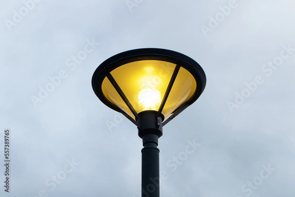 Fototapeta Light bulb night lamp lighting for safety. vintage street lamp post lantern lanterns at the park or enable to be turned on at the party. with sky and clouds in background during nighttime.
