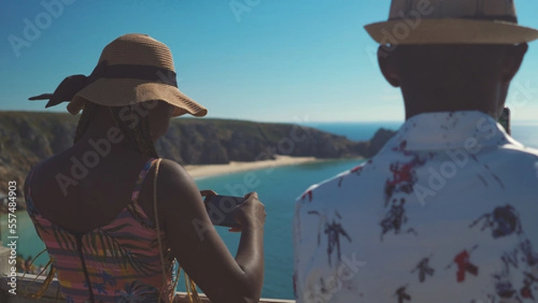Obraz Young beautiful African siblings in vacation in Cornwall united kingdom taking photos of surrounding    