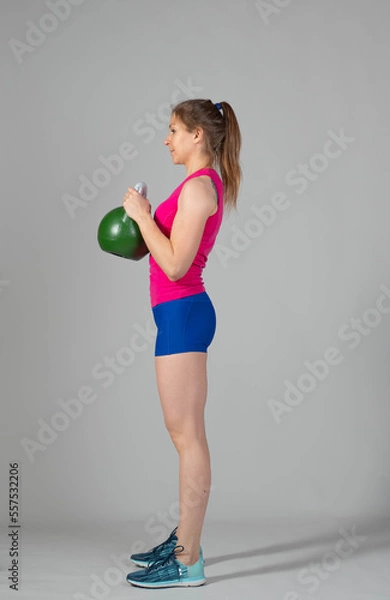 Fototapeta Training with kettlebells, a young athlete performs exercises with kettlebells, kettlebell lifting for the tone of the whole body