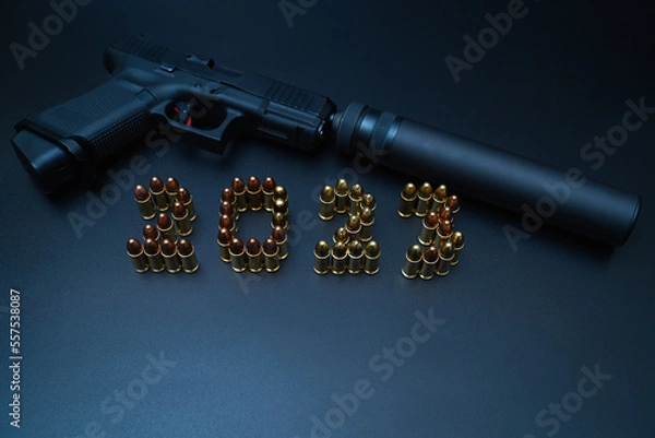 Fototapeta Happy new year 2023. Weapons, a pistol with a silencer and numbers from 9mm cartridges.