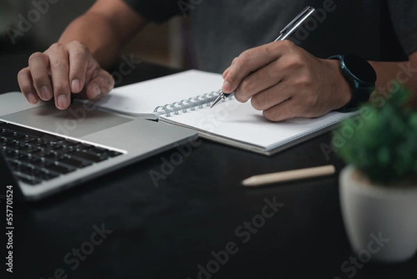 Fototapeta man hands with pen writing on notebook in the office.learning, education and work.writes goals, plans, make to do and wish list on desk.