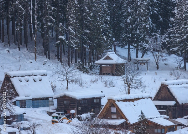 Obraz Steep roofs covered with snow in mountain village by woods