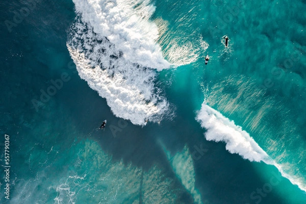 Fototapeta Spectacular aerial view of a surfer taking on waves in a blue ocean