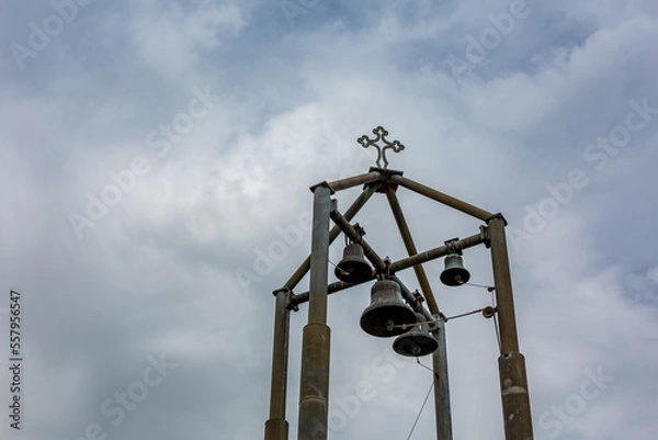 Obraz Contemporary metallic bell tower with four bells and cross in the sky