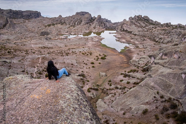 Obraz latina woman lying on a rock, with a lagoon and a valley of rocks in the background