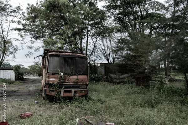 Fototapeta front view from a broken old truck that has been badly damaged abandoned in the middle of a park with scary vibes