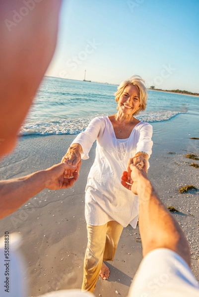 Fototapeta Happy Old Retired Senior Couple Dancing Holding Hands on a Beach