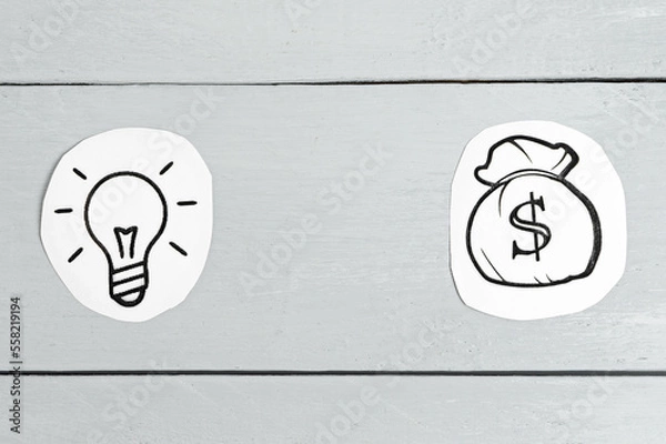 Obraz idea concept. Paper light bulb and bag with money on a gray background