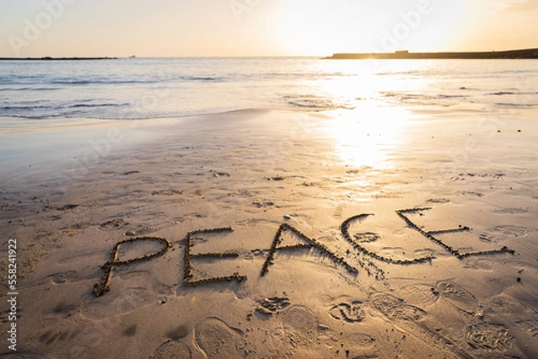 Fototapeta "Peace" written on the sand at the beach during sunset, photo with copy space.