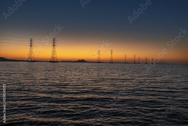 Fototapeta 바다에 설치된 송전탑과 그 뒤로 보이는 석양