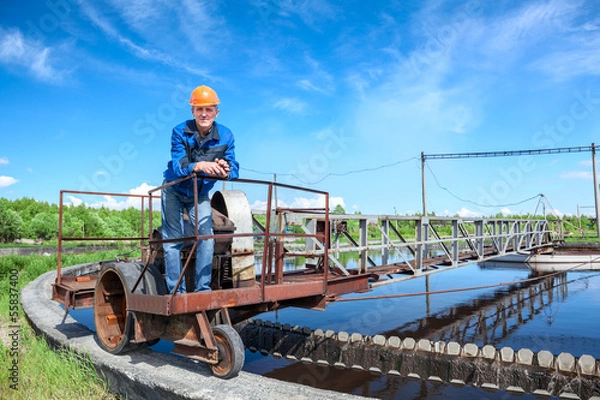 Fototapeta Senior worker standing on waste water treatment unit on plant