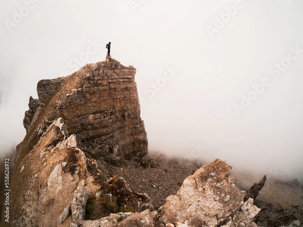 Fototapeta Silhouette of a lone tourist over a cliff. Sharp rocks. Mystical